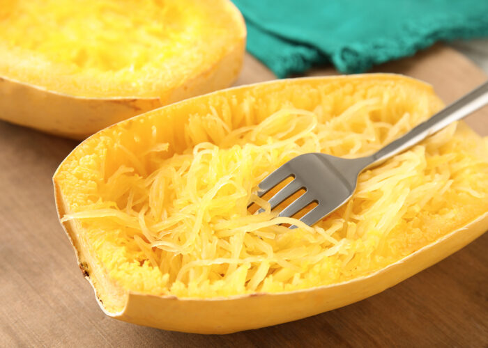 Scraping out the strands of a spaghetti squash with a fork. 