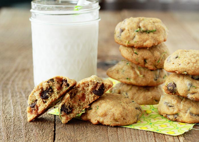A group of zucchini chocolate chip cookies with a glass of milk in the background