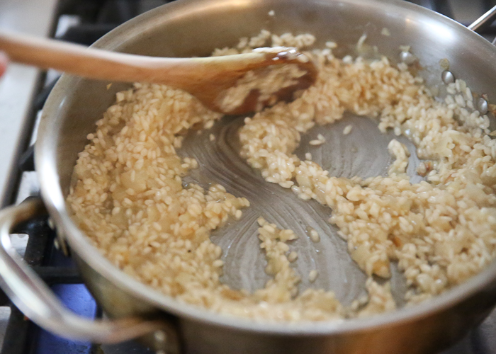 An image or a wooden spoon stirring risotto in process - demonstrating what risotto should look like before adding more broth. 