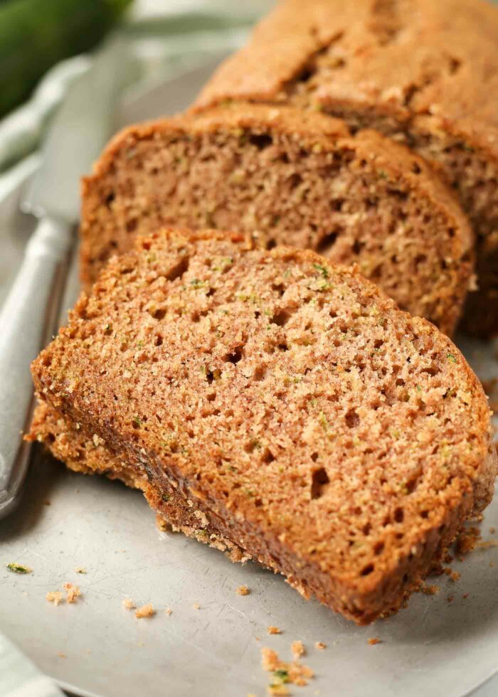 A slice of tender zucchini bread sits on a platter ready to be eaten. 