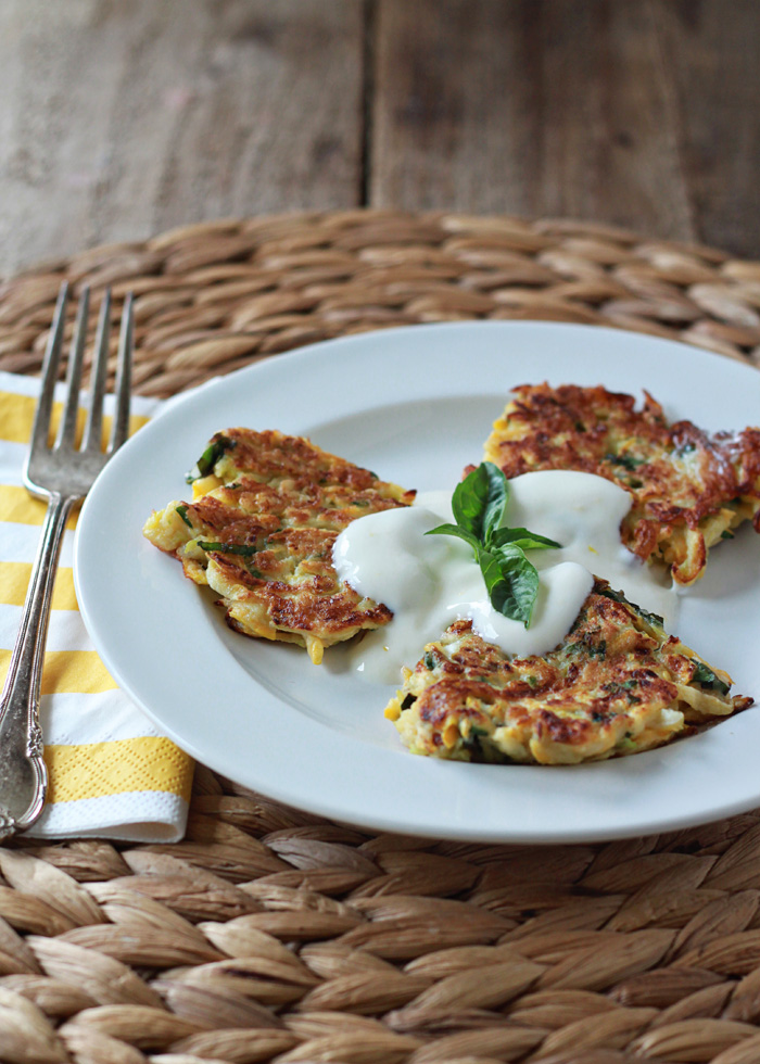 Crookneck squash fritters on a plate with a napkin and a fork. 