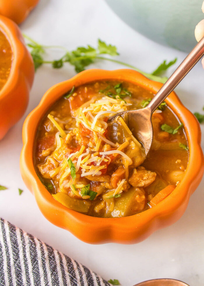 A bowl of turkey pumpkin chili with a spoon in it
